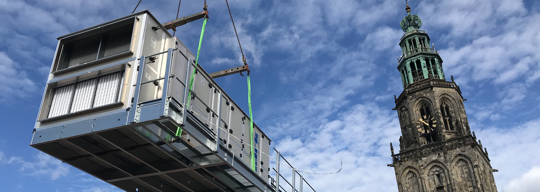 Een in de lucht gehesen Airstream WTW unit met de Martinitoren op de achtergrond